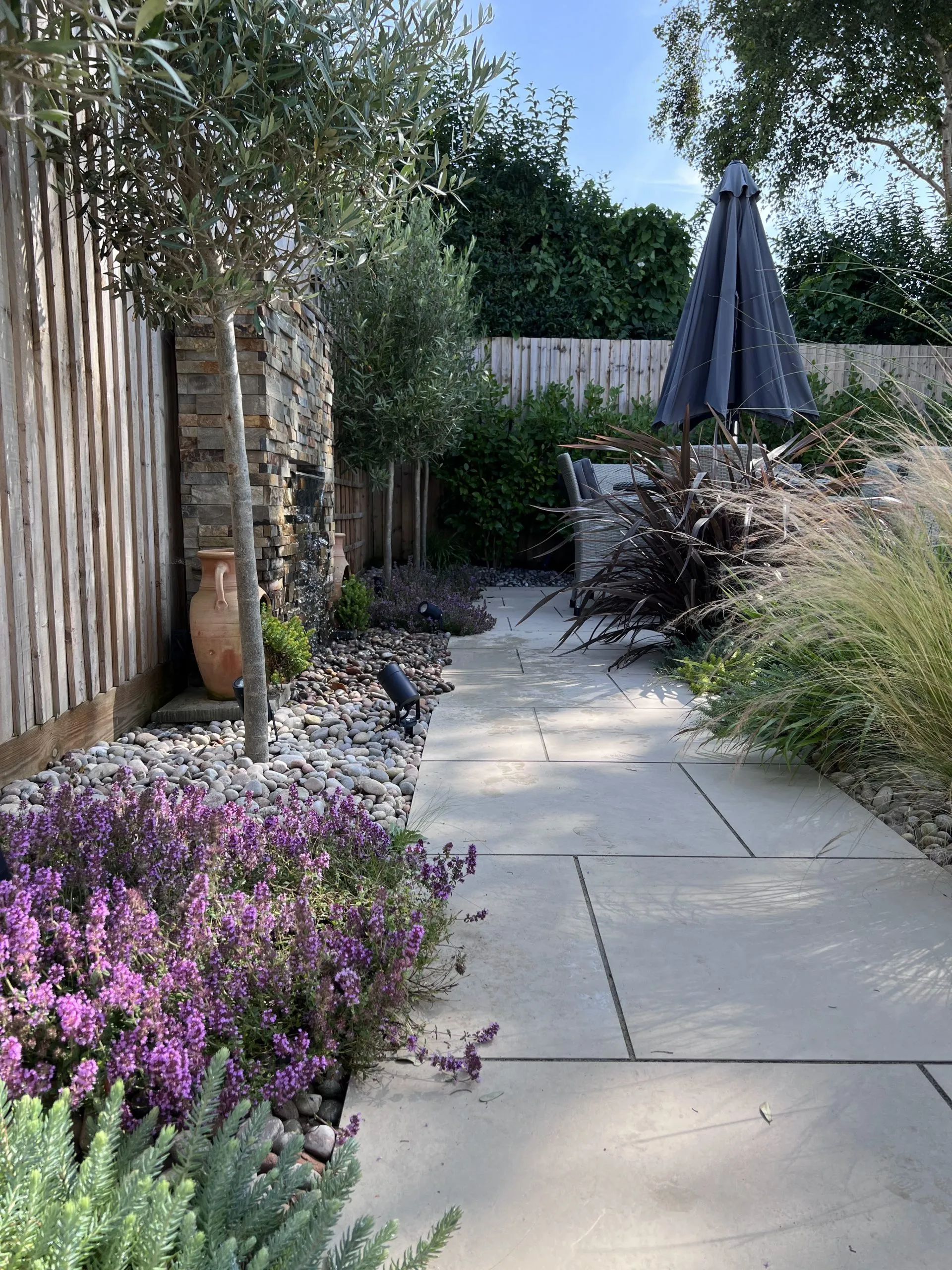 A porcelain paved path next to a waterfall feature.
