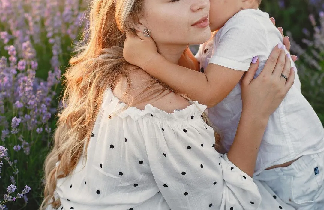 Mother holding her son in a field of lavender plants. A well-designed garden for neurodiverse wellbeing.