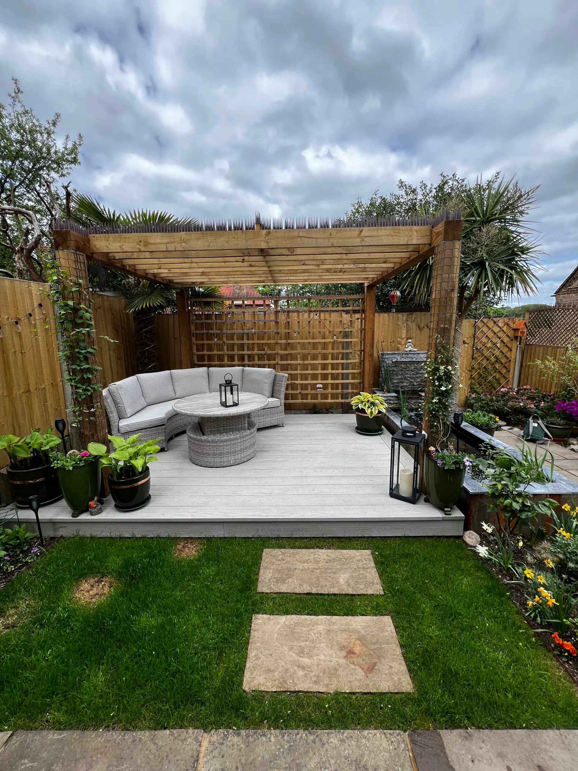 Pergola and small garden A photo of a garden makeover with a wooden pergola on decking and a water fallfeature in the background.