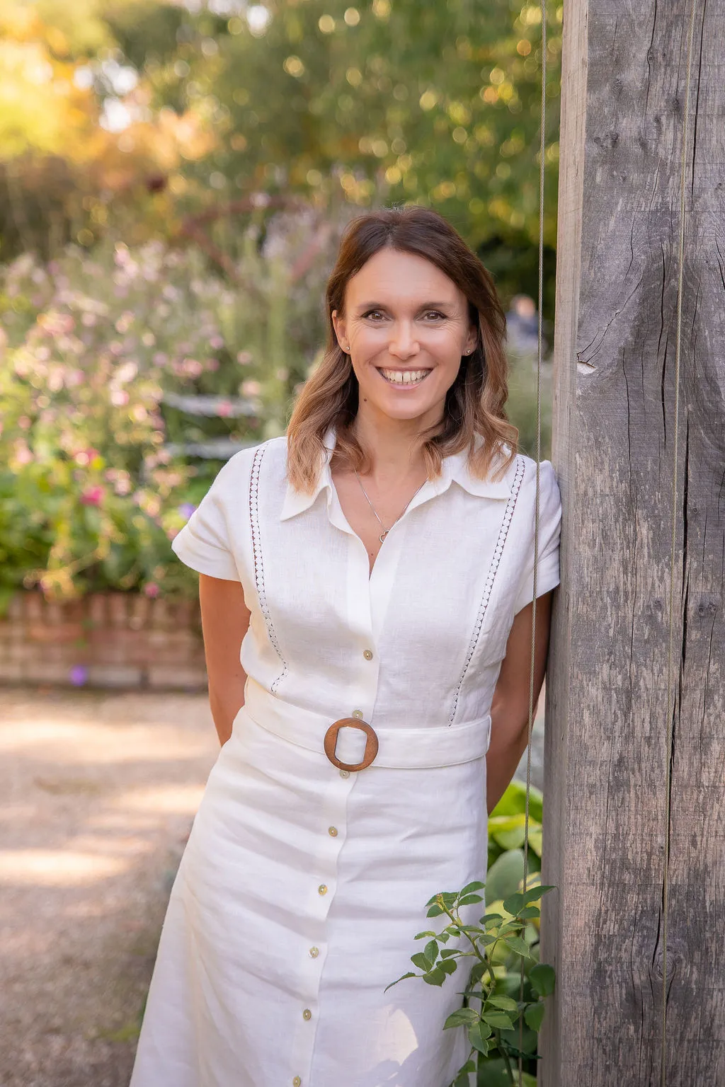 Victoria Rumens Garden Designer Victoria Rumens leaning against a wooden arbout in a stunning garden