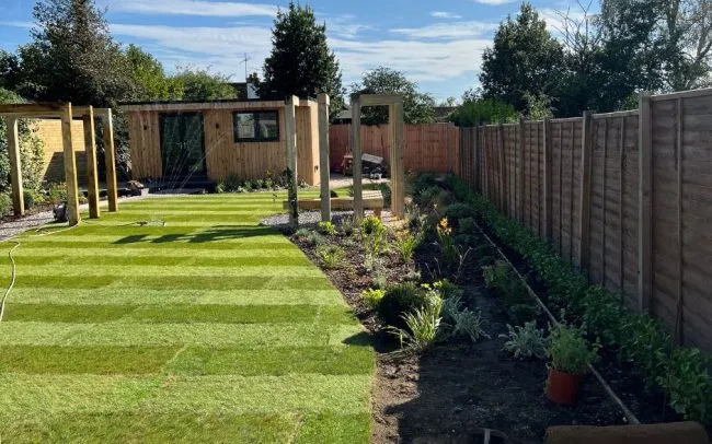 Completed garden design in Sussex with new lawn and planting beds as well as wooden bench and structures for climbing plants.